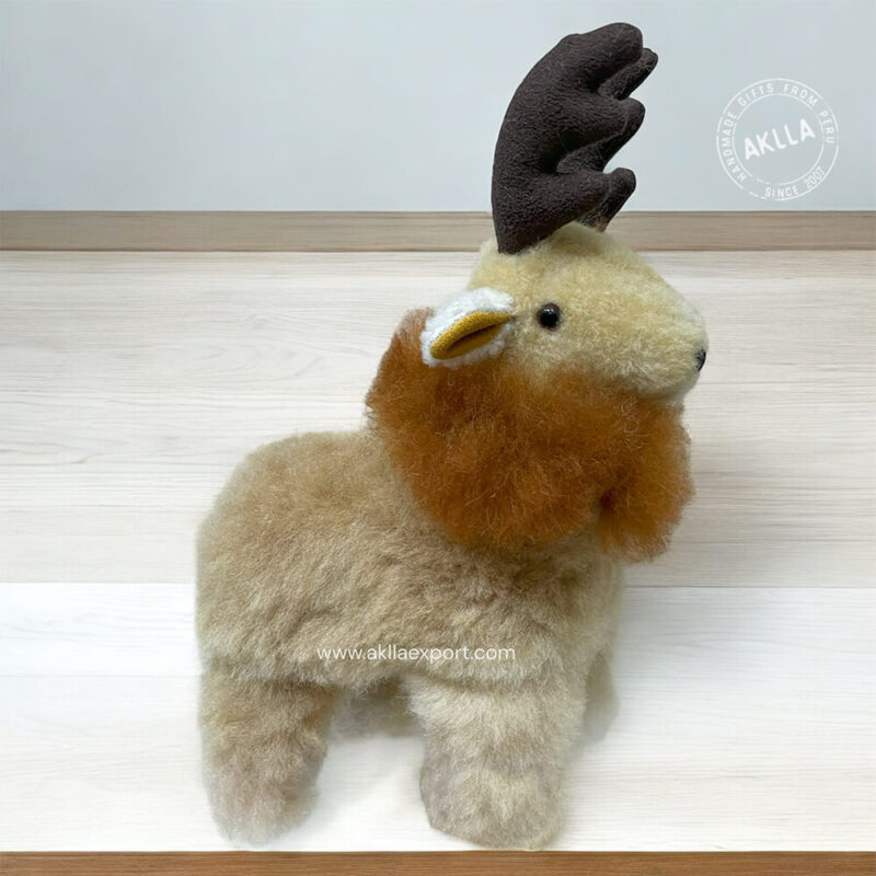 Alpaca stuffed animal designed as a reindeer, featuring soft, plush fur, festive antlers, and a bright red nose. The toy is shown in a cozy setting, highlighting its cuddly and charming design.