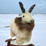 Reindeer plush toy made of soft alpaca fur, sitting on ice with festive antlers and a red nose, creating a winter-themed scene.