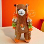 Front view of handmade llama stuffed toys with colorful woven saddles from Peru