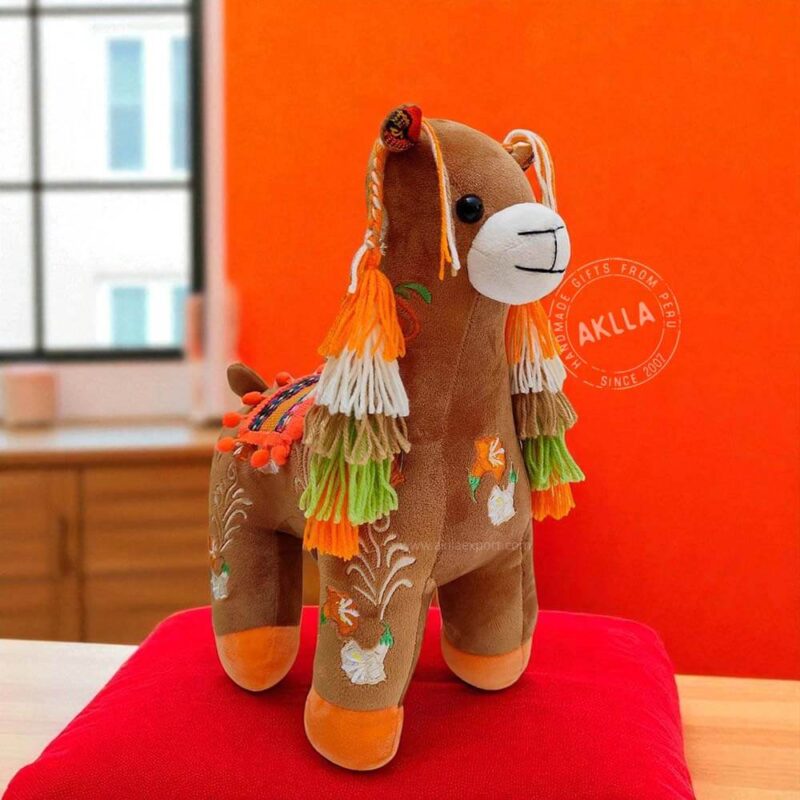Side view of Peruvian handmade llama stuffed toys with textile saddles and pompons