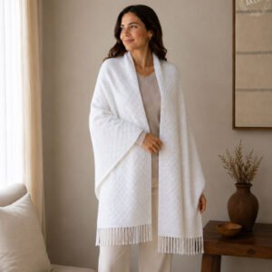 Woman wearing white 100% baby alpaca shawl wrap with textured weave and fringe indoors