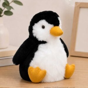 Handmade alpaca stuffed toy penguin in black and white alpaca wool sitting on wooden desk with yellow beak and feet