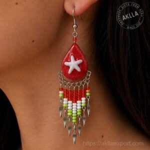 Side profile close-up of handmade beaded earrings showing resin teardrop starfish bead fringe and silver leaf detail