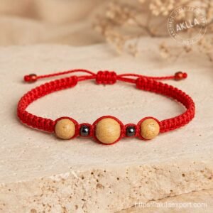 Handmade palo santo bracelet with red macramé band hematite beads and wood beads on stone surface