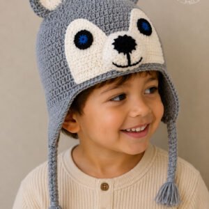Boy wearing handmade crochet wolf hat in gray with 3D ears blue eyes earflaps and tassels