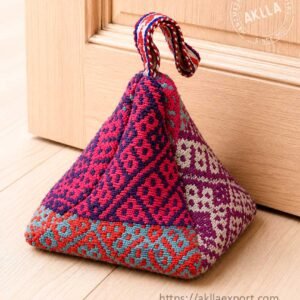 Handwoven Andean door stopper in 100% sheep wool pyramid shape with geometric pattern against wooden door